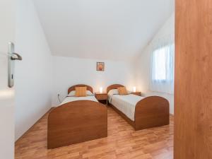 two beds in a room with white walls and wooden floors at Apartment in Vrsi near the Sea in Vrsi