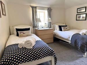 MAYS COTTAGE - Blakeney في بلايكيني: غرفة نوم بسريرين مع نقاط البولكا