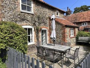 MAYS COTTAGE - Blakeney في بلايكيني: طاولة مع مظلة أمام المنزل