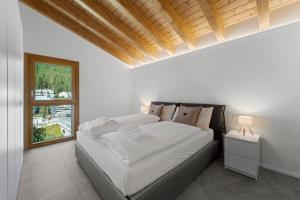 a white bedroom with a large bed and a window at Abitaziun Stauffacherin 3 - Pontresina in Pontresina