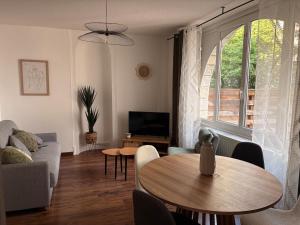 a living room with a table and a tv at Le Clos Mignon in Besançon