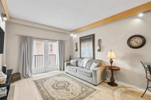 a living room with a couch and a clock on the wall at 301 Tuscan Breeze Getaway | Palm Coast in Palm Coast +30 photos