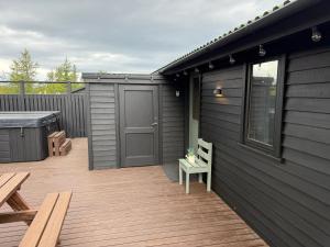 a deck with a door and a table and benches at Salmon River Cabin in Þingeyjarsveit
