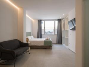 a bedroom with a bed and a couch and a window at Shabolo Apartments Las Palmas in Las Palmas de Gran Canaria