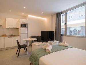 a bedroom with a bed and a table and a kitchen at Shabolo Apartments Las Palmas in Las Palmas de Gran Canaria