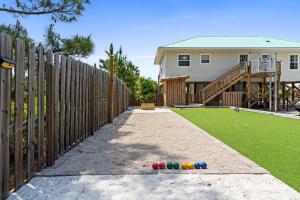 a fence with colorful balls on the ground in front of a house at Stay Salty by Coastline Vacation Rentals in Cape San Blas +66 photos