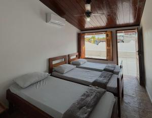 two beds in a room with a window at Casarão Boutique Casaboa in Itacaré
