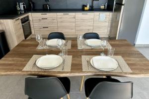 a wooden table with chairs and plates and wine glasses at Air-conditioned Apartment with terrace in Illkirch-Graffenstaden