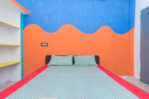 a bedroom with a bed with an orange and blue wall at Sai Rooms in Puducherry
