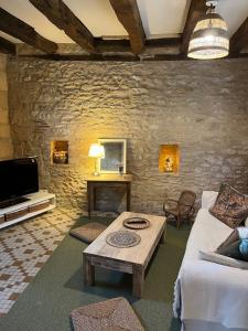 una sala de estar con un sofá y una mesa en Le chemin des écoliers 4 couchages, jardin, en Beynac-et-Cazenac