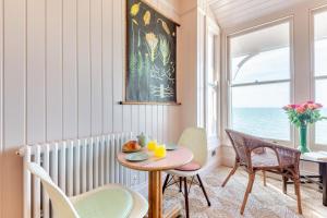 Un comedor con mesa y sillas y una ventana. en Iluka, en Herne Bay