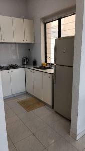 a kitchen with white cabinets and a refrigerator at sri sayang apartment in Batu Ferringhi