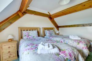 Dos camas en un dormitorio abuhardillado con techos de madera. en The School House, en Walton West