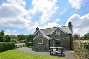 una casa de piedra con una mesa de picnic delante de ella en The School House, en Walton West