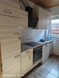 eine Küche mit Holzschränken und einem Herd mit Backofen in der Unterkunft Ferienwohnungen Schallenberg Nr 2 in Groß-Umstadt