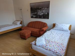 ein Schlafzimmer mit einem Bett, einer Couch und einem Stuhl in der Unterkunft Ferienwohnungen Schallenberg Nr 2 in Groß-Umstadt