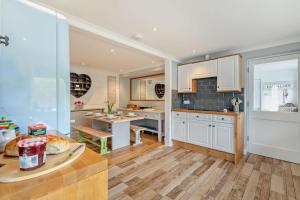 a kitchen with white cabinets and a table in it at The Beach House - Porthcurno in Saint Levan +18 photos