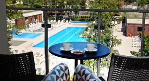 einen Tisch mit zwei Tassen Kaffee auf einem Balkon mit Pool in der Unterkunft Apartamenty BalticON Polanki in Kołobrzeg