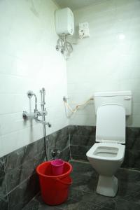 a bathroom with a toilet and a red bucket at Dream House in Satara