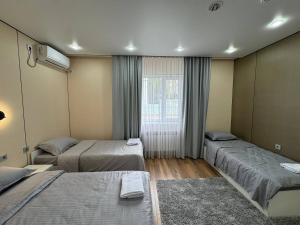 a room with three beds and a window at Damir HOTEL ГОСТИНИЦА in Aktobe +54 photos