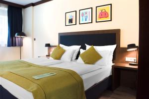 a hotel room with a large white bed with yellow pillows at Garner Hotel Frankfurt - Palmengarten by IHG in Frankfurt/Main