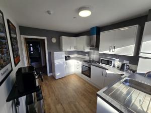 a kitchen with white appliances and a wooden floor at PRIME Breaks in Manchester