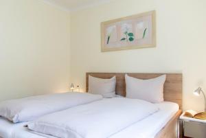 two white beds in a bedroom with a picture on the wall at Ferienwohnung Seestern in Timmendorfer Strand