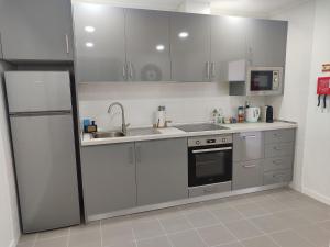 a kitchen with white cabinets and a sink and a refrigerator at Calço da Figueira in Horta