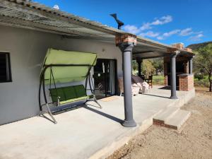 a green chair sitting on the back of a house at Gamtoosberg Cottage in Oudtshoorn