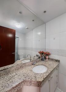 une salle de bain avec deux lavabos et un grand miroir dans l'établissement Santorini 2507-Bueno, à Goiânia