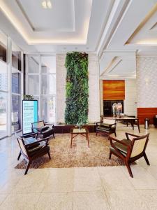 un hall d'entrée avec des chaises et une grande plante au mur dans l'établissement Santorini 2507-Bueno, à Goiânia