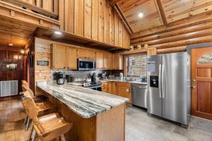 a kitchen with wooden cabinets and a stainless steel refrigerator at Moonlit Mountain Lodge by American Patriot Getaways in McCookville