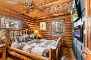 a log cabin bedroom with a bed and a flat screen tv at Moonlit Mountain Lodge by American Patriot Getaways in McCookville