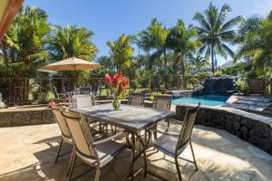 a dining room table with chairs and a pool at Honu Hale Sunrise in Princeville