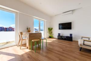 a living room with a desk and a table and chairs at Almada Comfort in Almada
