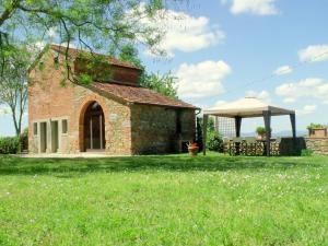 a brick building in a field with a gazebo at Cottage in Val di Chiana in Castiglion Fiorentino