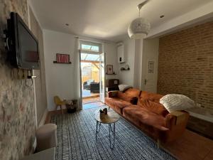 ein Wohnzimmer mit einer braunen Couch und einem Fernseher in der Unterkunft Maison IDEM in Vouziers