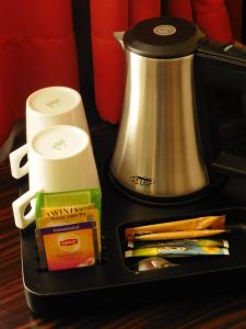 a tray with a tea kettle and packets of pencils at Hotel Empire in Luxembourg