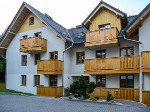 an apartment building with wooden balconies and a driveway at Apartament Królewski w centrum Nad Łomnicą 15 in Karpacz