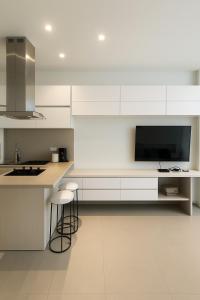a kitchen with white cabinets and a flat screen tv at Distrito 90 luxury suites in Barranquilla