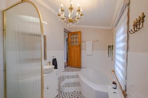 a bathroom with a chandelier and a tub and a sink at Blue Bell in Hermanus +57 photos
