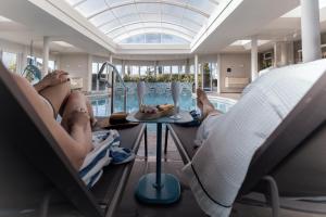 two people laying in chairs in a swimming pool at Hotel Casacurta in Garibaldi