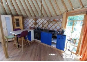 a kitchen with blue cabinets and a table in a room at Yourte in Aouste-sur-Sye