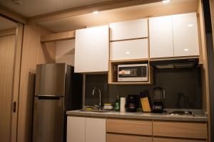 a kitchen with white cabinets and a stainless steel refrigerator at Indigo 513 - Apartamento con Piscina, Gym, Parking, Ubicación 10 de 10 in Armenia