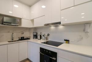 uma cozinha com armários brancos e um lavatório preto em The Modern by Wynwood House em Lima
