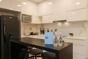 uma cozinha com um balcão preto com garrafas em cima em The Modern by Wynwood House em Lima