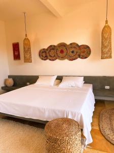 a bedroom with a white bed and some baskets at Casa Tartaruga Emboaca Trairí in Trairi