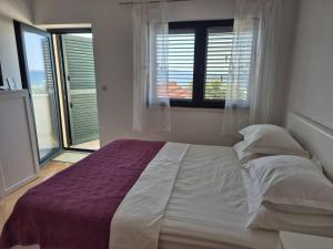 a white bed in a room with a window at Apartments with sea view in Kožino