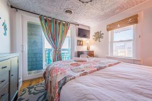 une chambre avec un grand lit et deux fenêtres dans l'établissement Deja Blue, à Kill Devil Hills