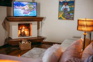 a living room with a fireplace and a tv at Lê Château Hotel de Gramado, seu refúgio no centro da cidade in Gramado